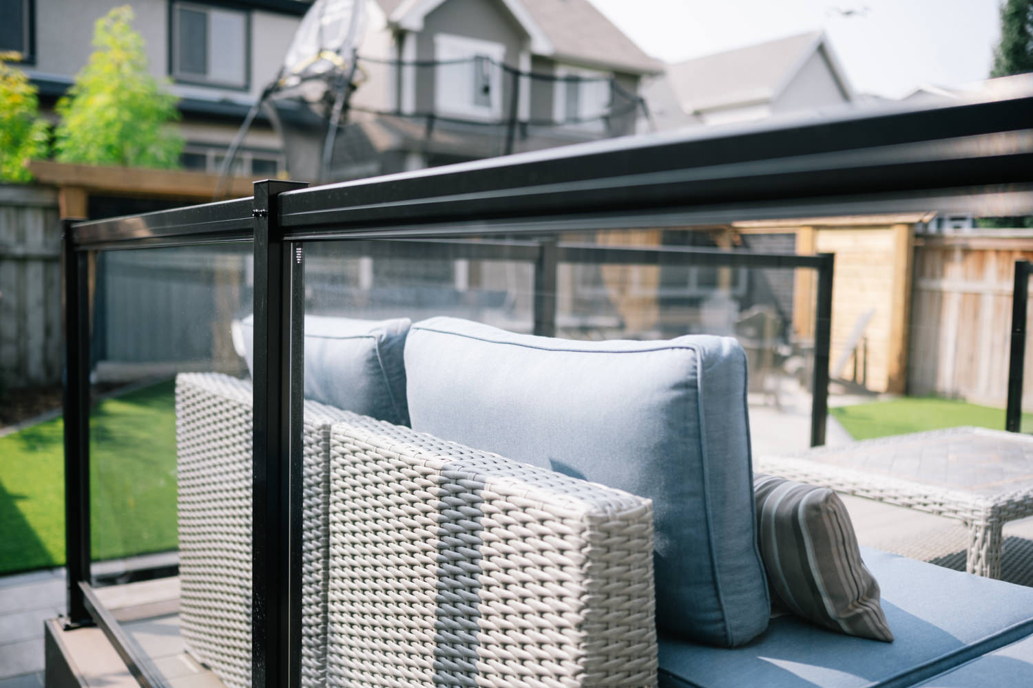 Outdoor patio seating area with woven furniture and cushions, showcasing a privacy screen in a Calgary backyard, part of the Mahogony 1 project by Kayben Landscaping.