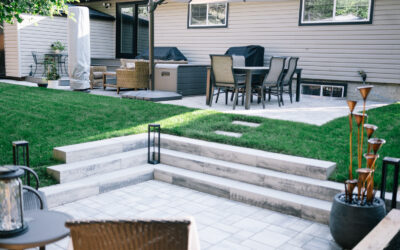 Residential backyard with landscaped patio, dining set, outdoor furniture, and decorative features, showcasing Kayben Landscaping's design and construction expertise.