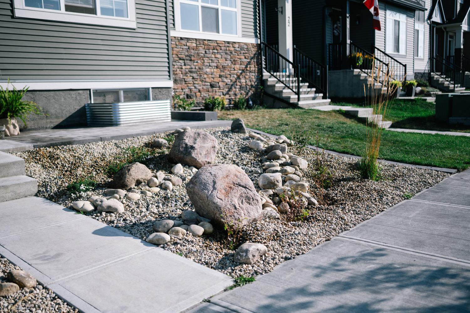 Xeriscape front yard design featuring large rocks, gravel, and native plantings in a residential setting in Wedderburn, showcasing sustainable landscaping practices.