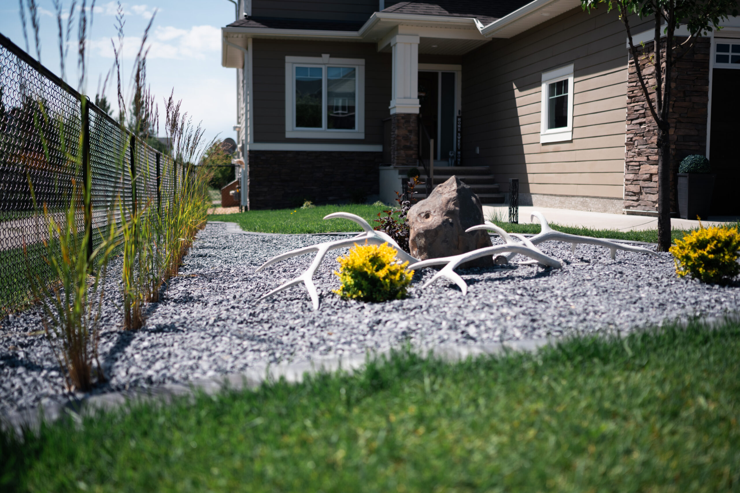 Air Ranch backyard in Okotoks with crushed gravel beds, stone patio, seating area, and edging