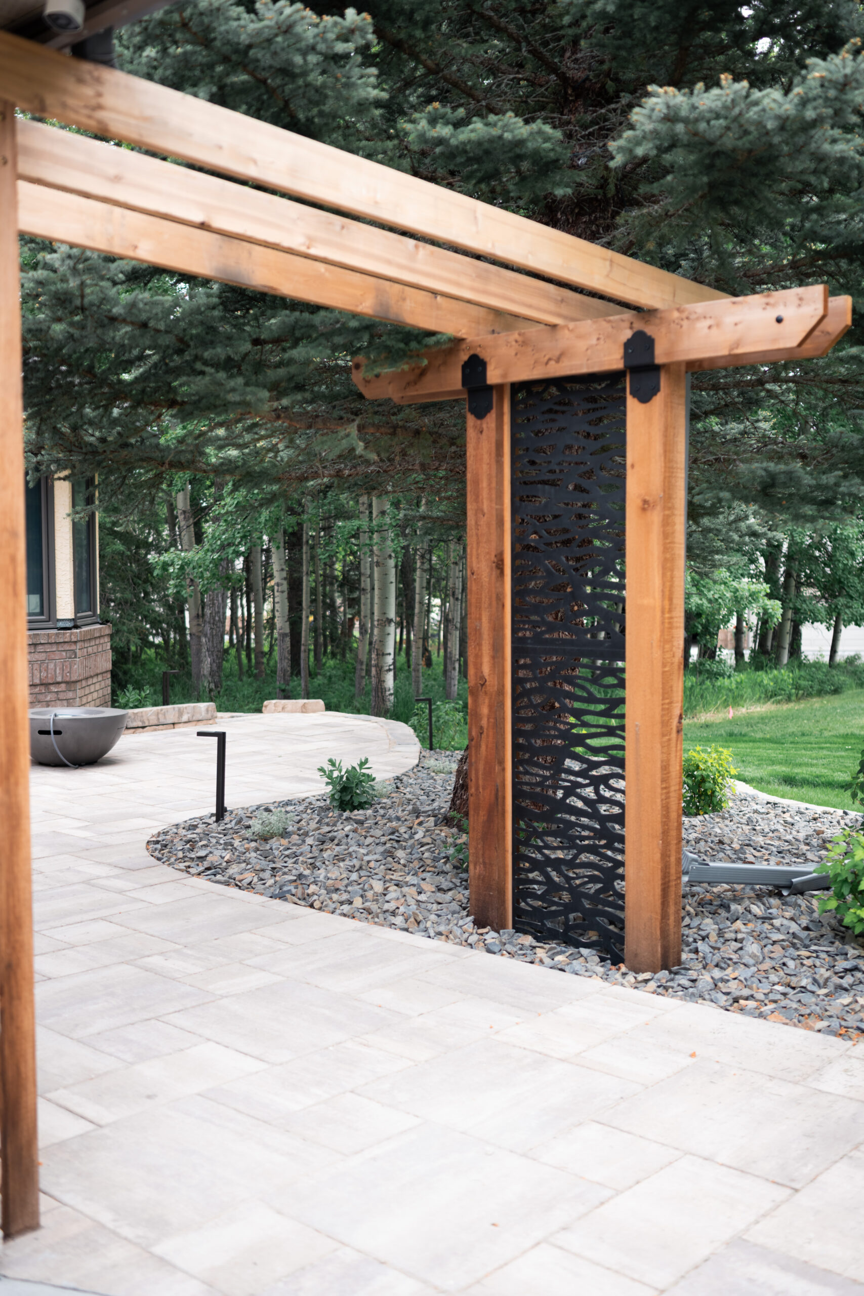 Pergola with stone patio walkway underneath in a Priddis and De Winton acreage estate yardThis acreage estate yard in Priddis and De Winton features a custom pergola with a stone patio walkway beneath, designed by Kayben Landscaping to bring shade, style, and flow to the outdoor space.