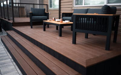 Contemporary outdoor living space featuring a wooden deck with stylish seating, coffee table, and decorative accessories, highlighting landscaping design by Kayben Landscaping.