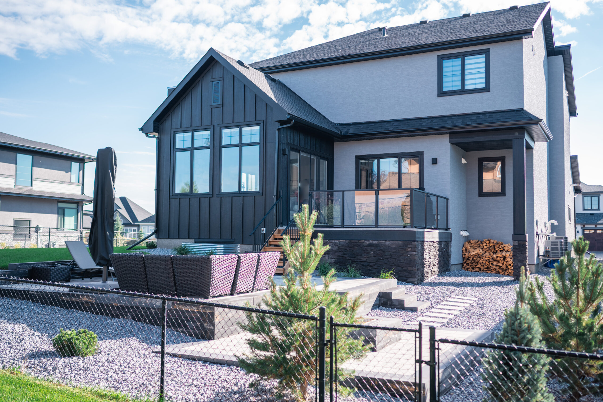 Modern residential home in Artesia at Heritage Pointe, featuring a stylish exterior, landscaped seating area with wicker furniture, and stone pathways, showcasing Kayben Landscaping's design expertise.
