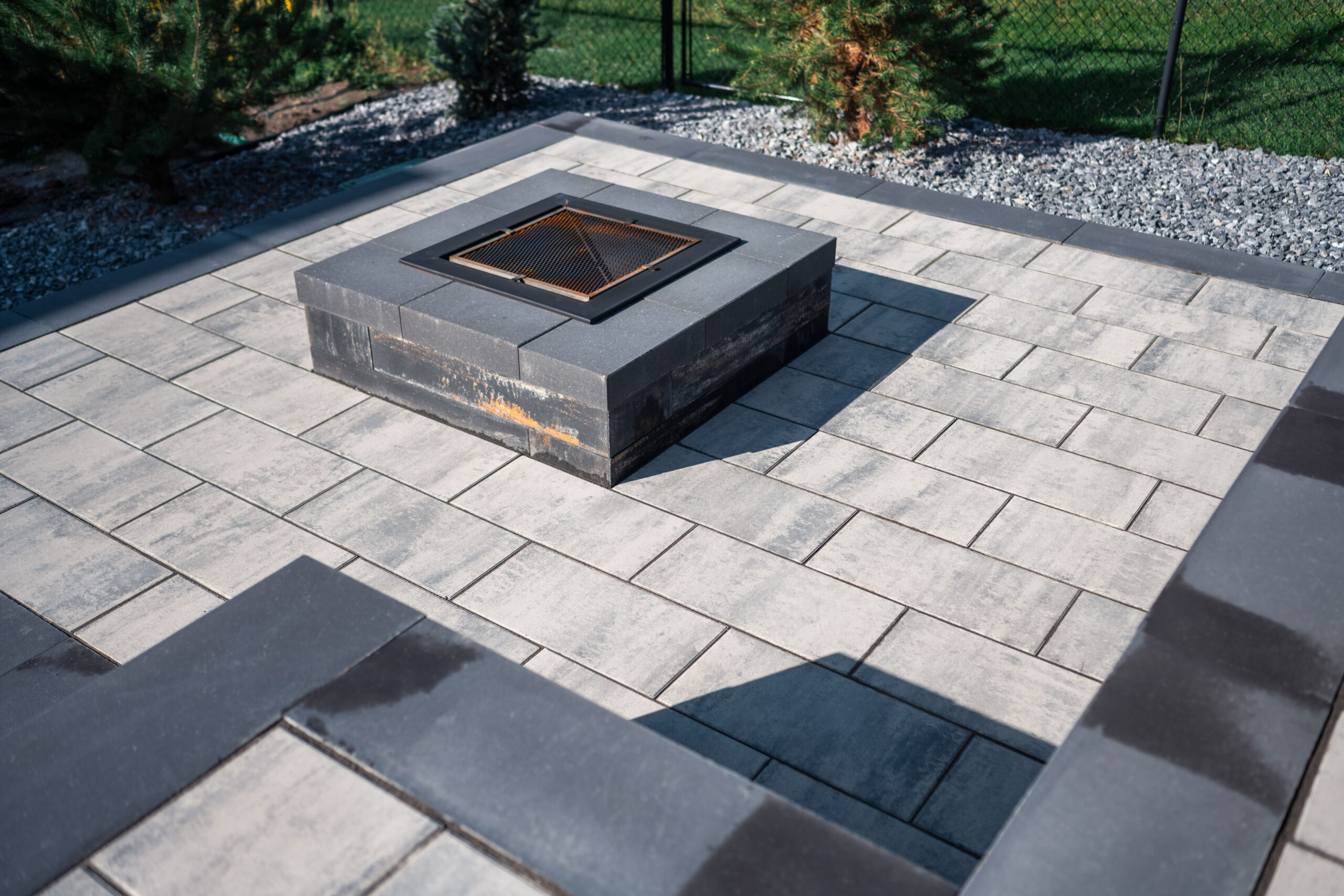 Paver patio featuring a modern fire pit surrounded by landscaping elements in Artesia at Heritage Pointe.