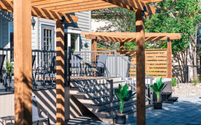 Wooden pergola and deck with stairs, featuring potted plants and outdoor seating, showcasing residential landscaping design by Kayben Landscaping in Okotoks, Alberta.