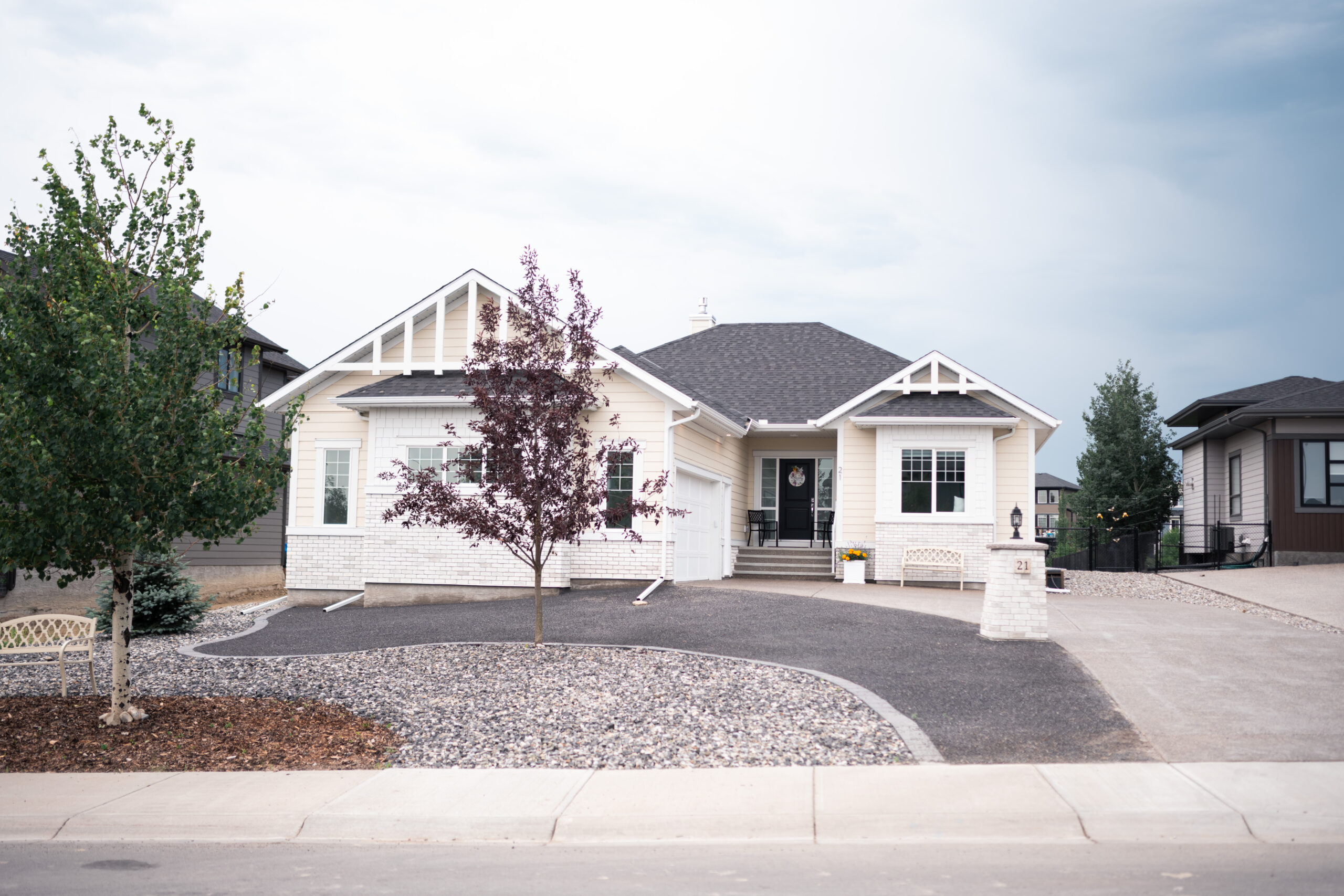 Cimarron Estates 4 residential landscaping featuring a modern home with stone accents, decorative trees, and gravel front yard design in Okotoks, Alberta.
